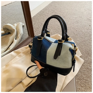 Detail of two-tone denim boston bag showing contrast stitching and gold hardware