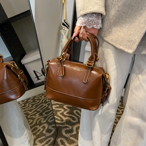 Sac Boston vintage marron avec surpiqûres blanches et garnitures dorées porté main