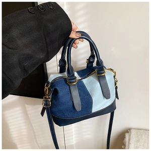 Detail of denim patchwork Boston bag with leather trim and premium gold hardware accents