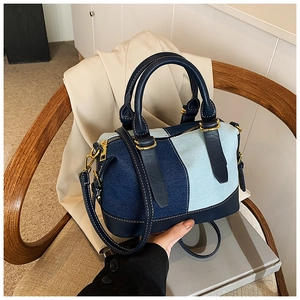 Detail of denim patchwork Boston bag with blue leather handles and gold-tone hardware