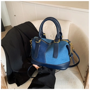 Detail of color-block denim Boston bag with gold hardware on a white chair