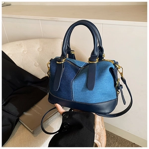 Detailed close-up of a denim patchwork Boston bag with leather trim and gold hardware