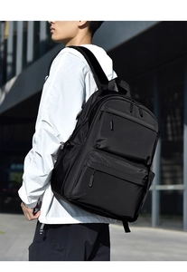 Outdoor shot of a black nylon laptop backpack showing wide ergonomic straps and side pocket