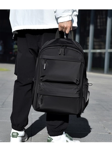 Detailed view of black nylon backpack with double zipper front pockets and wide handle