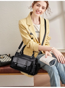 Détail du sac à main en cuir noir avec boucles doubles et rivets porté par un mannequin