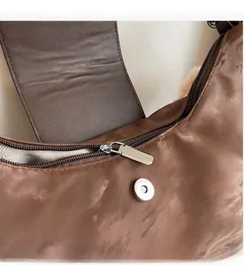 Detail eines glatten Reißverschlusses und Magnetverschlusses an einer braunen Tasche