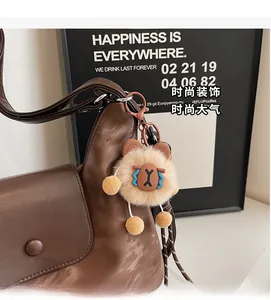 Detail eines süßen Plüschbären-Anhängers mit braunem Karabinerhaken an Handtasche