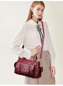 Détail du sac à main en cuir bordeaux avec doubles boucles et bandoulière réglable amovible
