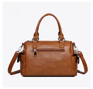 Vue détaillée de la poche arrière et texture en cuir PU grainé du sac boston brun