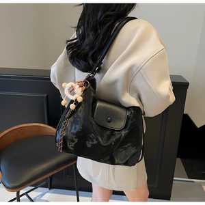Details einer schwarzen matten Ledertasche mit Schaffell-Anhänger und Klapptasche