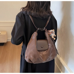 Detail eines braunen Tote-Rucksacks mit Lederklappe und einem süßen Schaf-Plüschanhänger