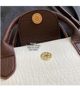 Detail of magnetic snap closure on two-tone pebbled leather bag with gold-tone hardware