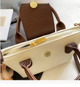 Detail view of smooth golden zipper and lychee grain leather on the beige handbag
