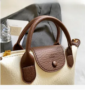 Detail of beige hobo bag with brown leather flap and golden zipper hardware