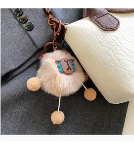 Plush brown bag charm with long faux fur and spring clasp on white leather handbag