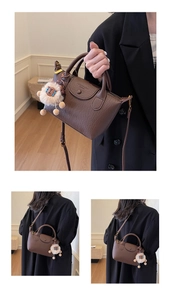 Detail of brown leather dumpling bag with shoulder strap and cute sheep charm pendant
