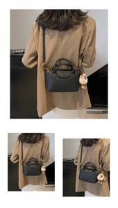 Detail of black pebbled leather handbag with adjustable strap and cute sheep charm