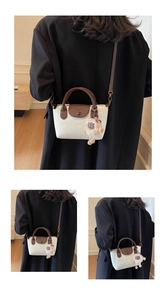 Detail of cream crossbody bag with brown leather handles and cute plush sheep charm