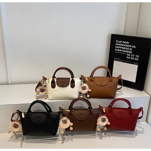 Detail of color-block dumpling bags in five shades with fluffy sheep charm accents