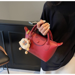 Detail der roten Tragetasche aus strukturiertem Leder mit Reißverschluss und Schafanhänger