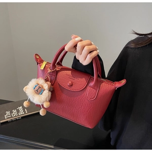 Detail der burgunderroten Lederhandtasche mit Litschi-Maserung und Schaf-Anhänger