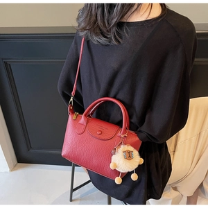 Detail der roten PU-Ledertasche mit Lychee-Muster, Plüschschaf-Anhänger und Schultergurt
