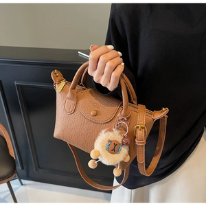 Model mit brauner Umhängetasche aus Leder mit Struktur und Plüschschaf-Anhänger