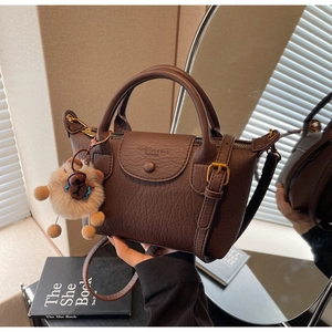 Detail der Litschi-Lederstruktur und Markenprägung auf der kaffeebraunen Handtasche