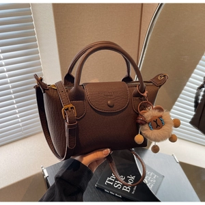 Detailansicht der braunen Handtasche aus Leder mit Litschimaserung und süßem Lamm-Anhänger