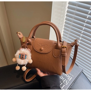 Detail der braunen Leder-Dumpingtasche mit Litschimuster und süßem Plüsch-Schaf