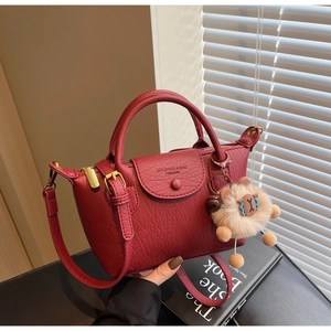 Detail der dunkelroten Mini-Tasche aus Narbenleder mit Plüschbär und langem Riemen