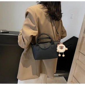 Detail of black wrinkled leather dumpling bag with white sheep charm and magnetic buckle