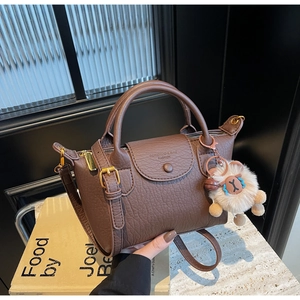 Details der braunen Lederhandtasche mit Narbenstruktur, Goldbeschlägen und Schaf-Anhänger