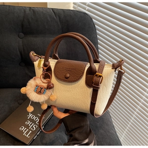 Detail der cremefarbenen Leder-Tasche mit brauner Klappe und Löwen-Anhänger