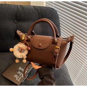 Detail der dunkelbraunen Faltenledertasche mit Metallteilen und Plüschtier-Anhänger