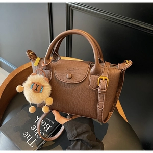 Details der braunen Handtasche mit Narbenlederstruktur und weichem Schaf-Anhänger
