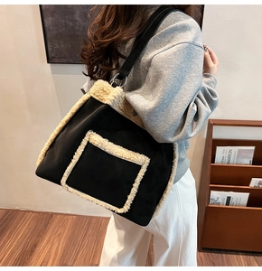Close-up of black oversized tote bag with cream faux fur trim and metal ring strap detail