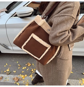 Brown suede tote bag with white fleece trim and large silver rings in autumn setting