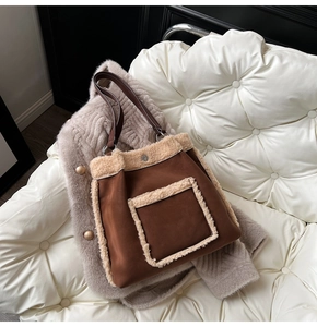 Macro view of brown suede tote bag featuring cream faux shearling trim and metal buckle