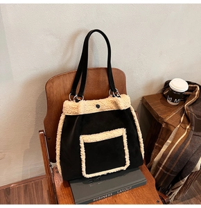 Fuzzy black suede tote bag with cream faux shearling trim on a wooden chair