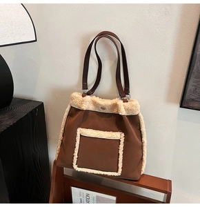 Detail of brown faux suede bucket bag featuring creamy shearling trim and metal hardware
