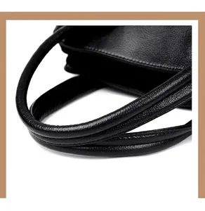 Detailopname van het zwart lederen handvat met textuur en gladde rand van de grote draagtas