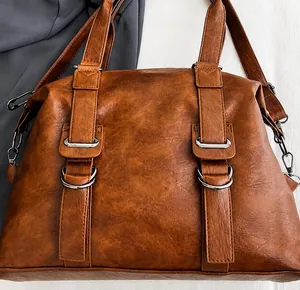 Detailed view of large brown tote bag with premium lychee grain texture and silver hardware