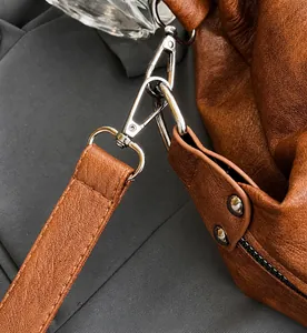 Detail of silver metal hook and stitched brown leather strap on luxury tote bag