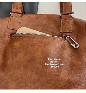 Macro detail of brown leather bag with functional rear zip pocket and metal paperclip zipper