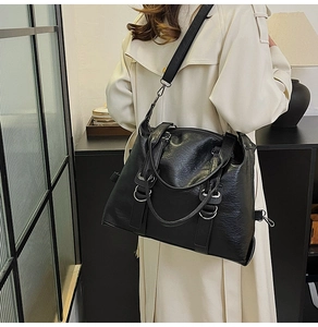 Rear view of a model wearing the large black textured tote bag with silver metal ring details