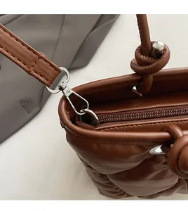 Détails de la texture en cuir matelassé marron avec fermeture éclair et boucle en métal