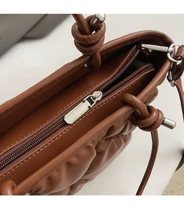 Détail de la fermeture éclair argentée sur le sac matelassé marron à texture luxueuse