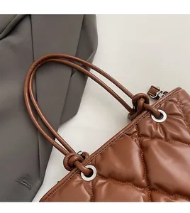 Gros plan détaillé du sac à main en cuir matelassé marron avec anses nouées et œillets