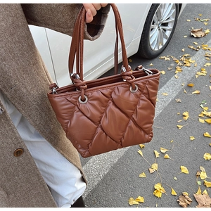 Gros plan sur un sac seau matelassé marron foncé avec motif de losanges et anneaux argentés